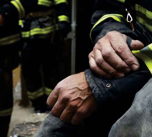 Firefighter hands close up holding sore arm